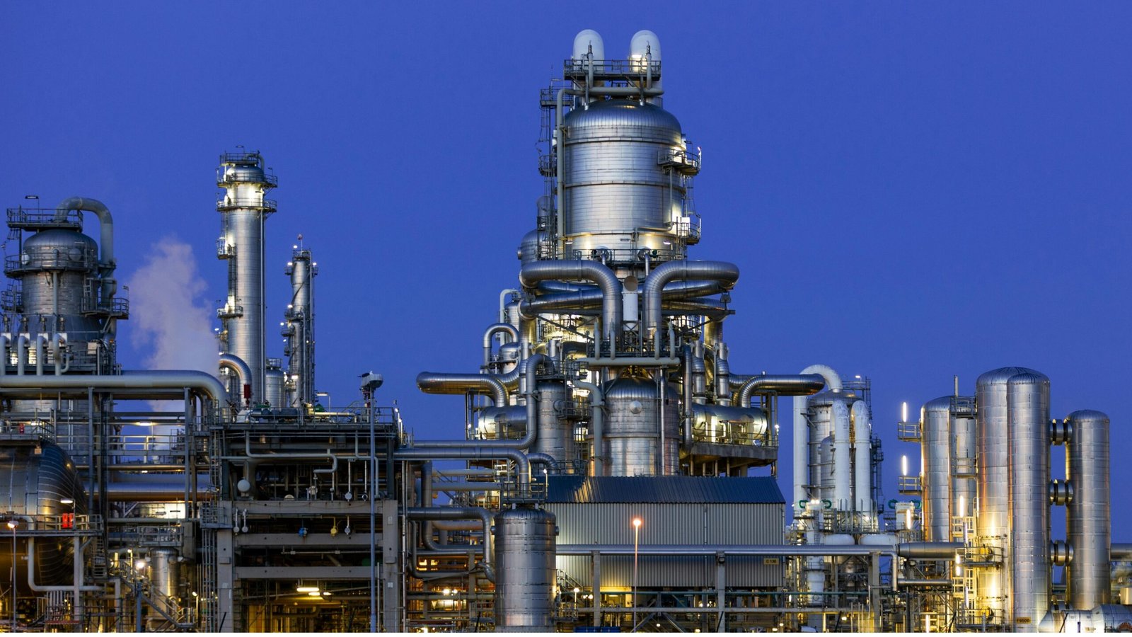 Large industrial processing plant with extensive steel piping, towers and tanks at dusk.